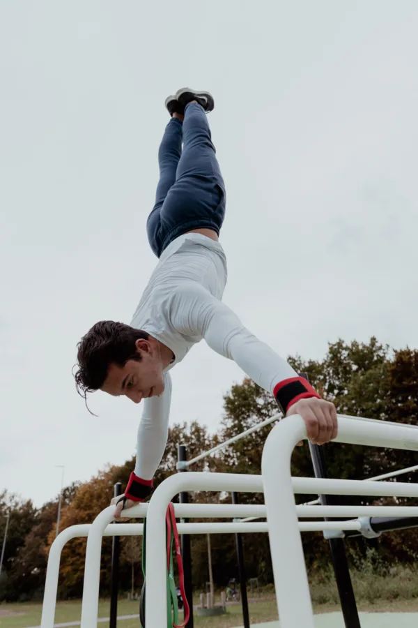 Handstand op parallelbars met rode Croffit Wristwraps